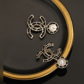 Сережки Chanel из черного металла с бледно-золотыми элементами. С