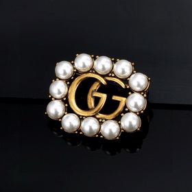 Брошь Gucci с двойным G. Этот элемент является символом бренда и