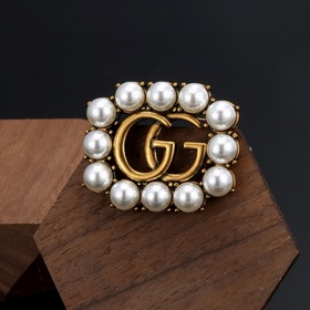 Брошь Gucci с двойным G. Этот элемент является символом бренда и 